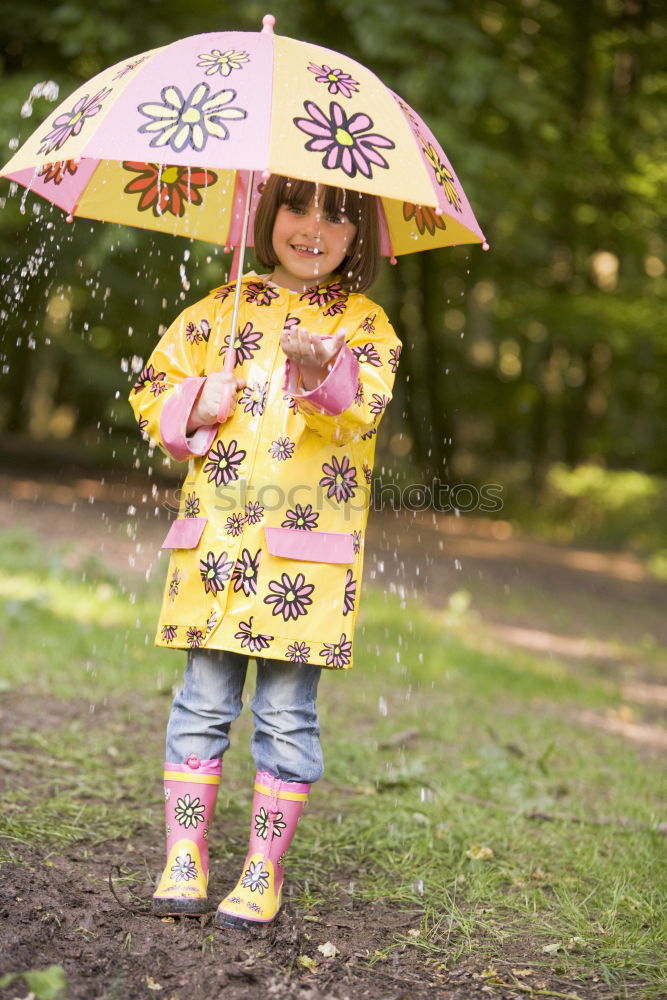 Similar – Image, Stock Photo Child in a raincoat with umbrella crouched down playing and laughing in a puddle