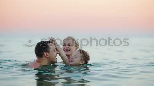 Similar – Image, Stock Photo Mother kissing her young child while bathing in the sea waters during sunset