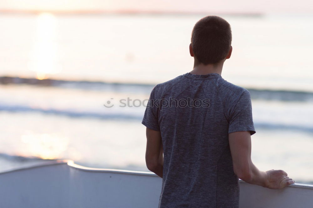 Similar – Man with tattoos holding skateboard at shore. Back view.