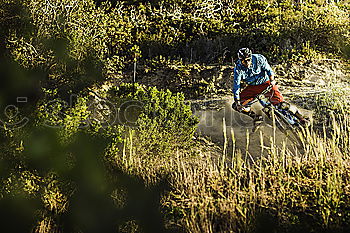 Similar – Downhill-Fahrer springt mit dem Fahrrad bergab und macht einen Peitschentrick