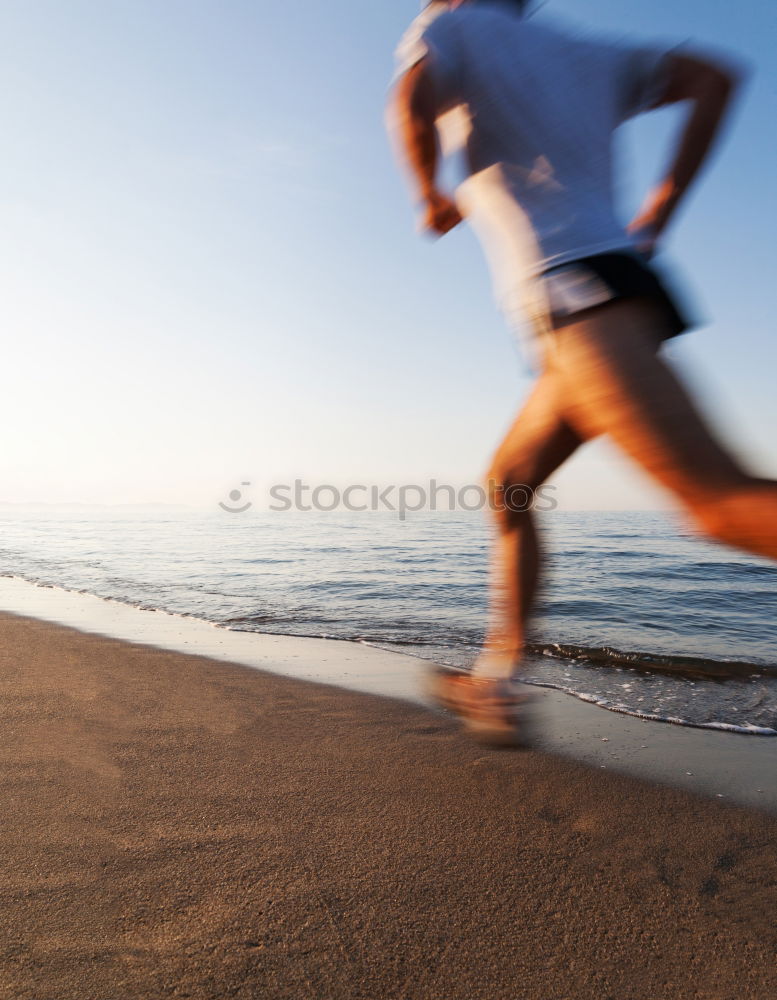 Man running at sunset on a sandy beach in a sunny day