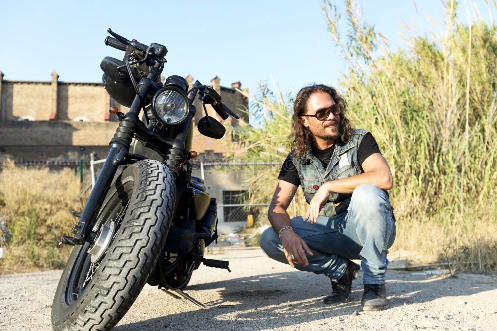 Similar – Long-haired brunette guy in sunglasses jeans and a jeans shirt posing on a black custom motorcycle