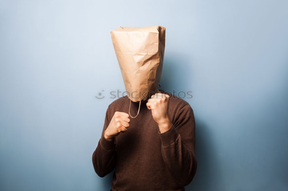 Person with paper bag on head pointing at camera