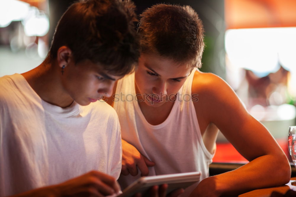 Image, Stock Photo Two male teenagers surfing the internet on tablet computer while sitting in cafe. One young man pointing at screen