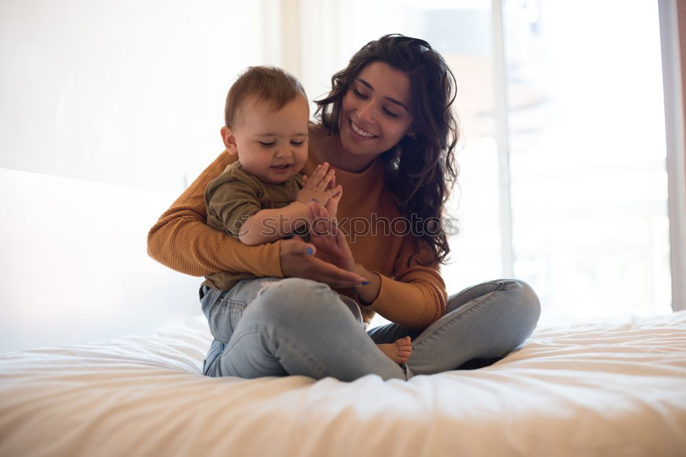 Similar – happy young mother and her baby boy lying on bed and smiling