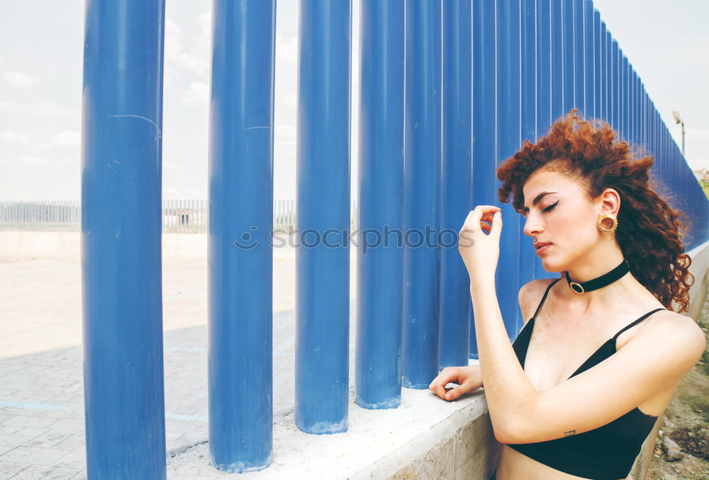 young redhead woman agains blue wall is sending a kiss