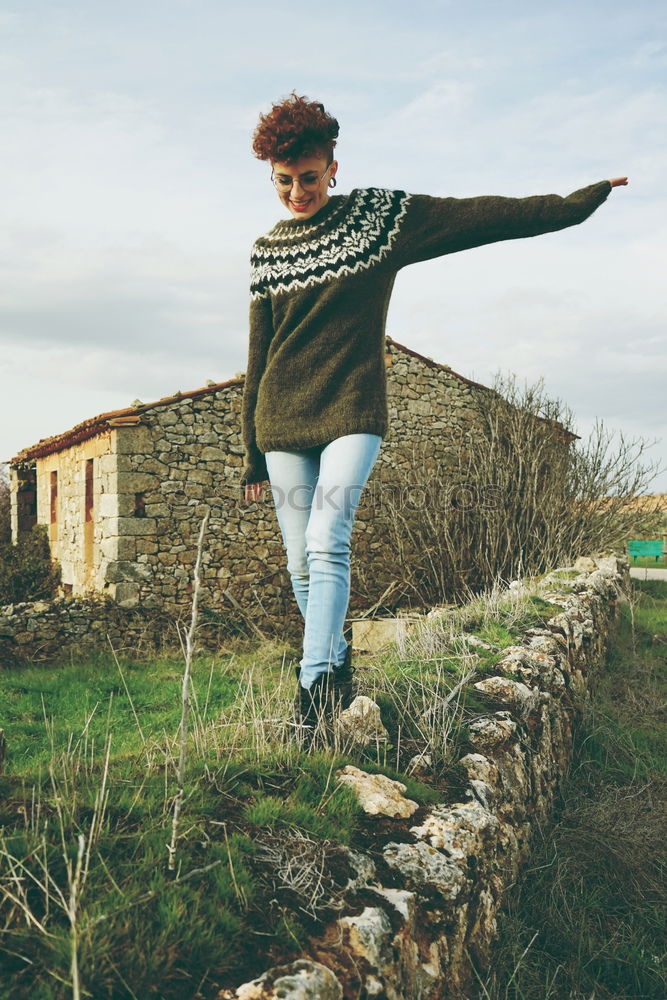 Young redhead woman walking along an old wall