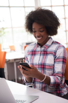 Beautiful afro american woman using mobile and laptop in the coffee shop.