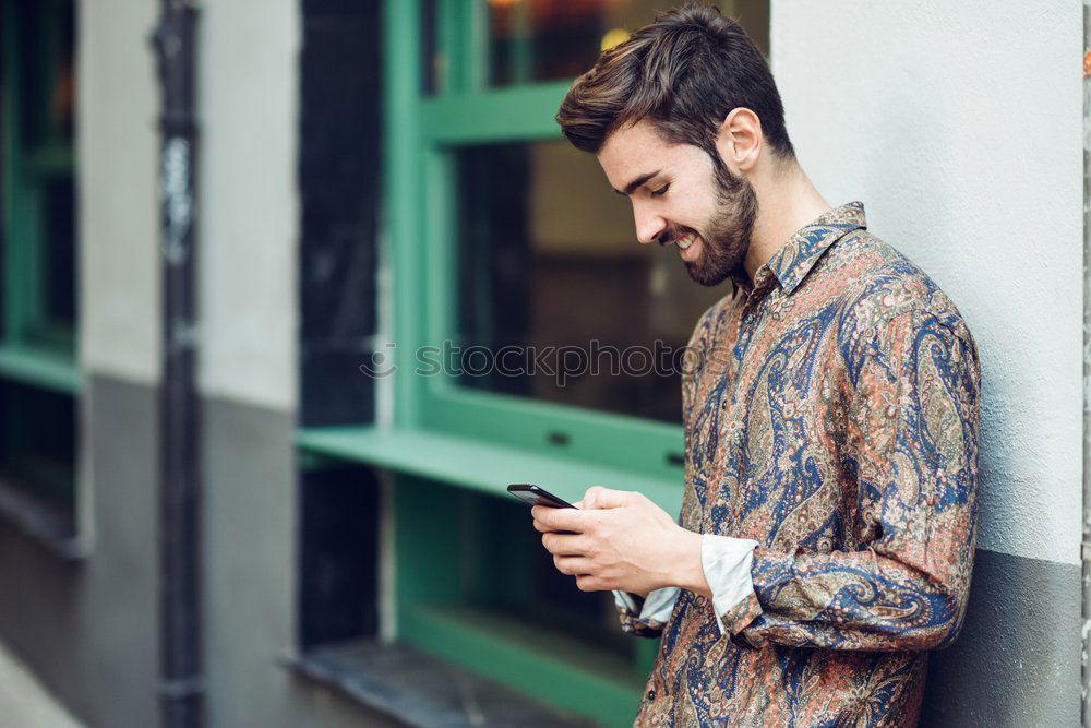 Image, Stock Photo Young smiling man looking at his smartphone in the street