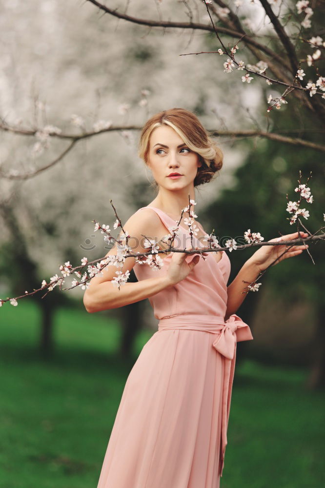 Young woman in almond flowered field in spring time