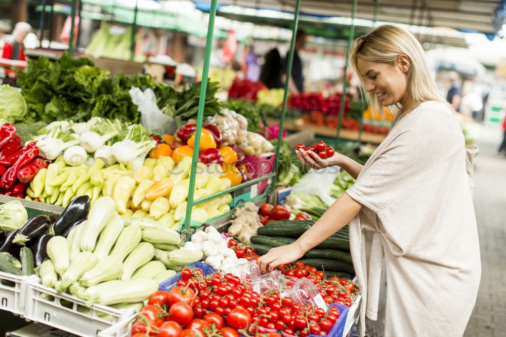 Similar – Image, Stock Photo Young woman shopping for fresh tomatoes at an open-air stall choosing items from a row of wooden boxes