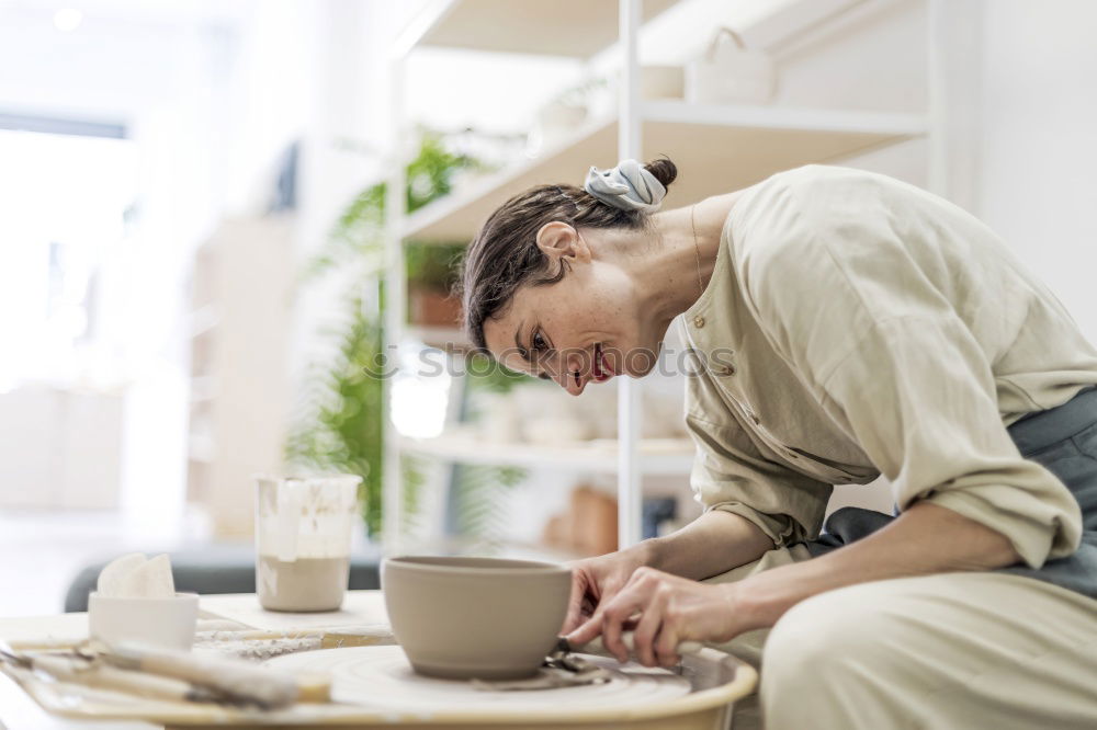 Similar – Image, Stock Photo Young female sitting by table and making clay or ceramic mug in her working studio