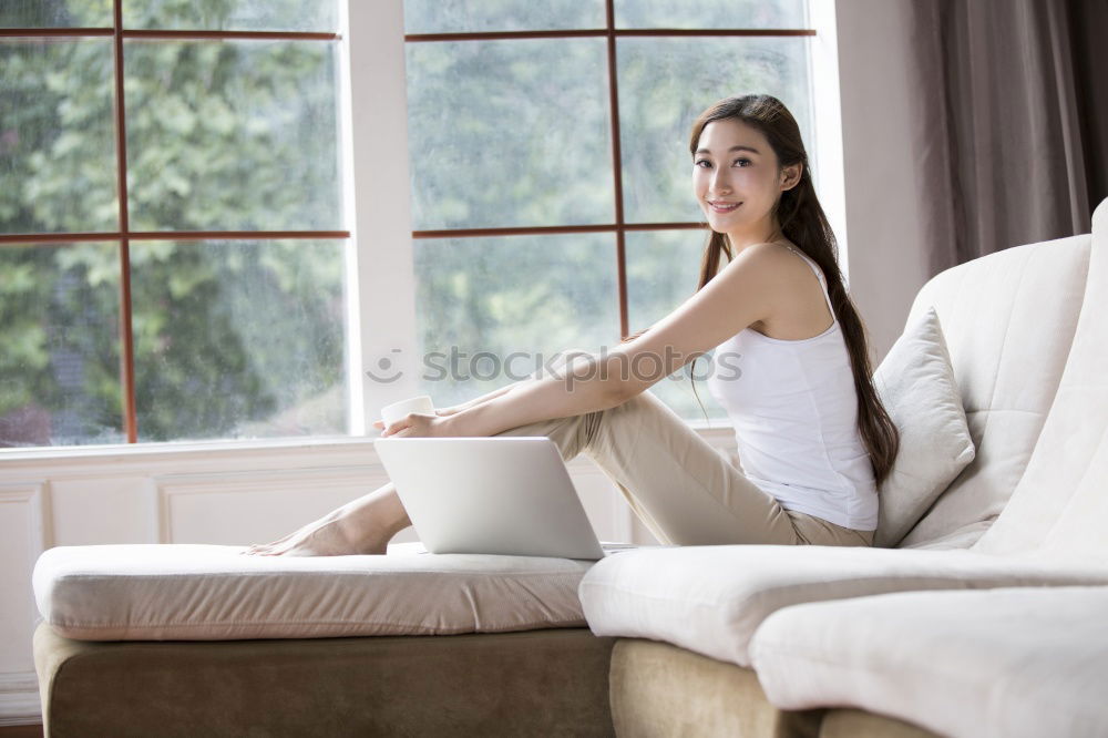 Similar – Image, Stock Photo Young woman with long legs sits barefoot on the edge of the couch and looks at the camera