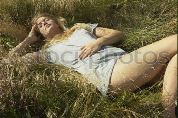 Young woman with turquoise hair sits barefoot in forest on beach and laughs loudly