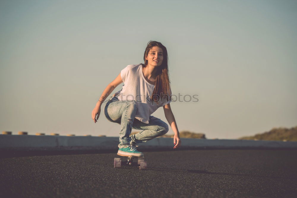 Happy female riding skate board in street