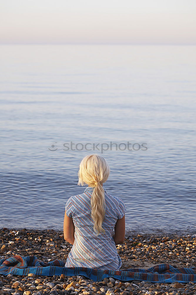 Similar – Rear view of a woman sitting on a wooden bench and looking at a lake