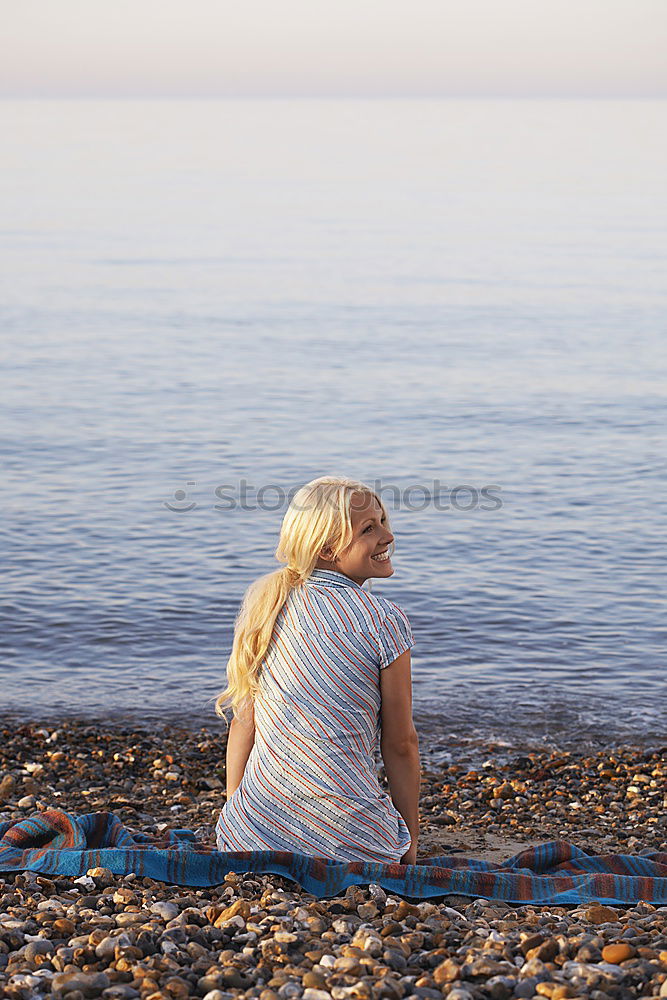 Similar – Rear view of a woman sitting on a wooden bench and looking at a lake