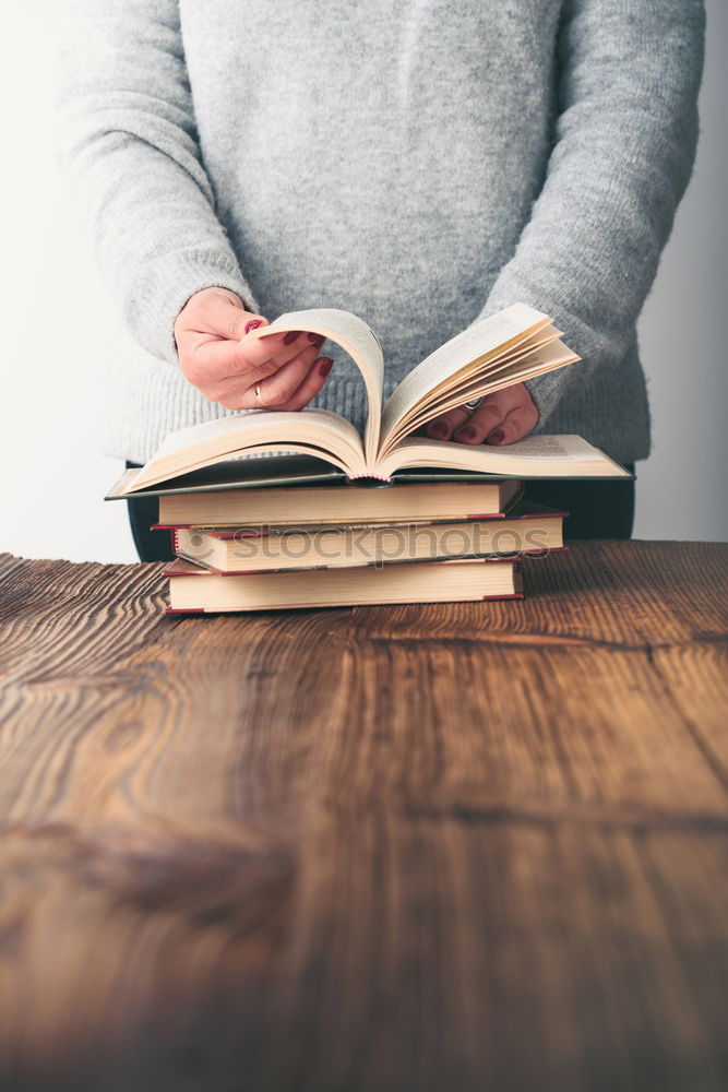 Similar – Woman turning pages of book on table in antique bookstore